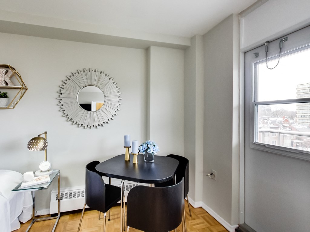 A black table with two chairs and a mirror on the wall.
