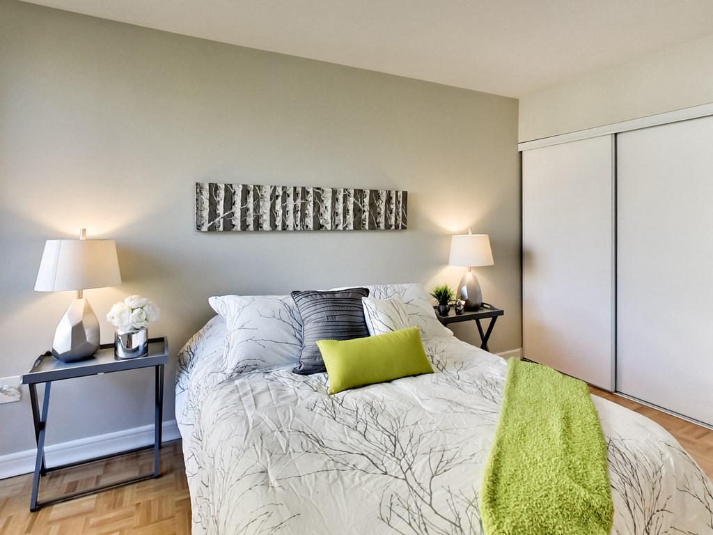 A bedroom with a bed, two lamps, and a green throw.