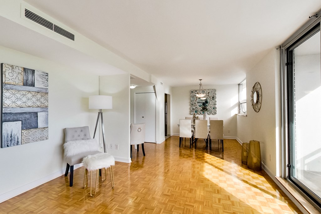 A room with a wooden floor and white walls has a chair and a table in it.