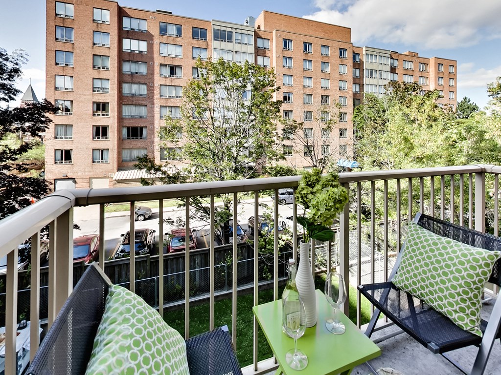 a balcony with two blue chairs and a green table
