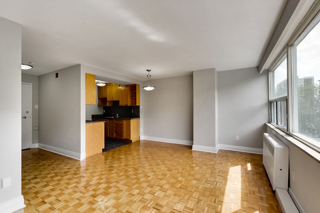 an empty living room with wood flooring and a kitchen