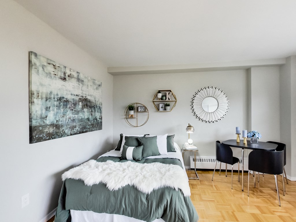 A bedroom with a bed, a table, and a chair.