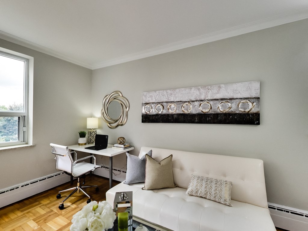 a living room with a white couch and a desk with a chair