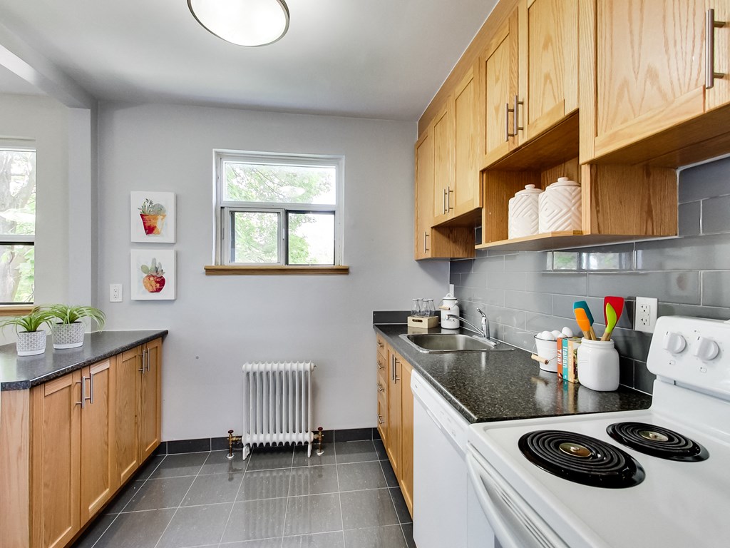 A kitchen with a white stove top oven and wooden cabinets.