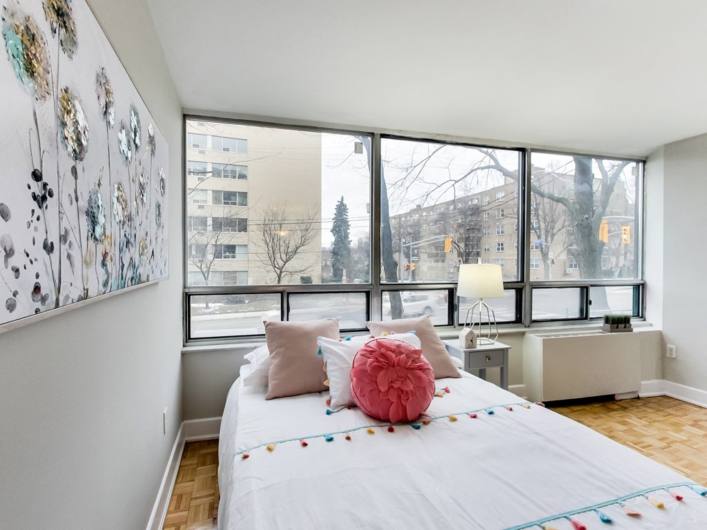 A bedroom with a large bed and a view of the city outside the window.