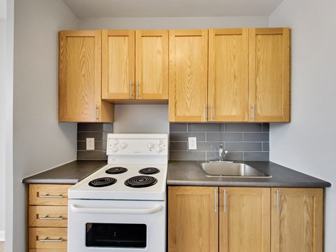 A kitchen with a white stove and wooden cabinets.
