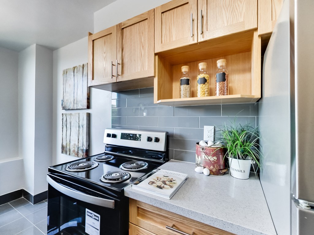 A kitchen with a black stove top oven and wooden cabinets.