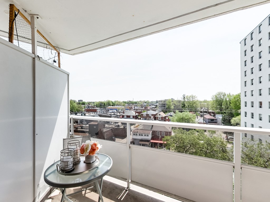 A balcony with a table and chairs overlooking a cityscape.