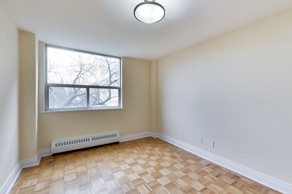 A room with a window and a radiator on the floor.