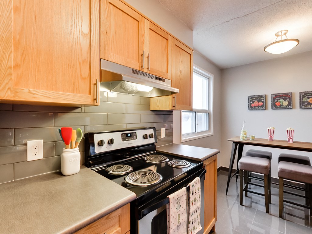 a kitchen with wood cabinets and black appliances and a stove top oven