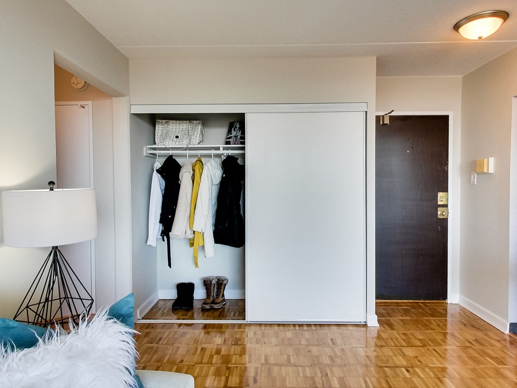 a living room with a white closet with clothes hanging on it