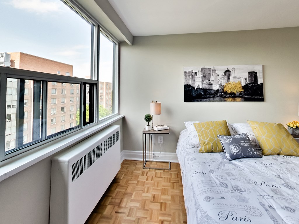 a bedroom with a large window and a bed with yellow pillows