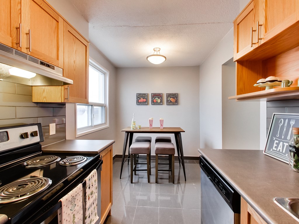 view of kitchen and dining room with wood cabinets and appliances and a table with chairs