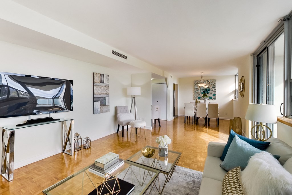 A living room with a glass coffee table and a white couch.
