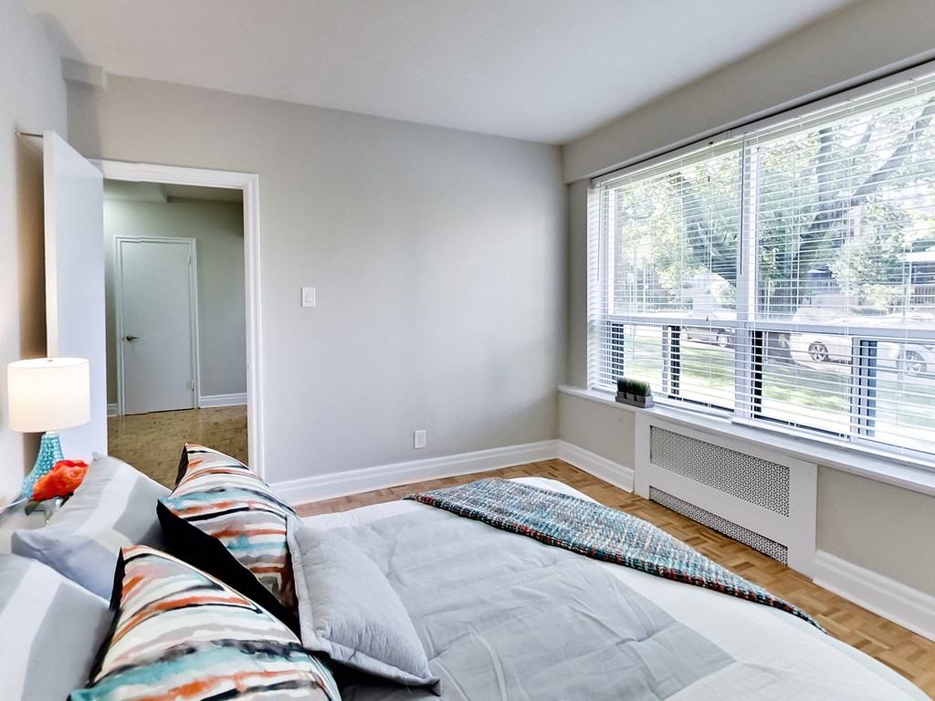 a bedroom with a large window and a bed with pillows