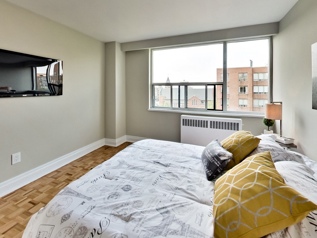 a bedroom with a large window and a bed with yellow pillows