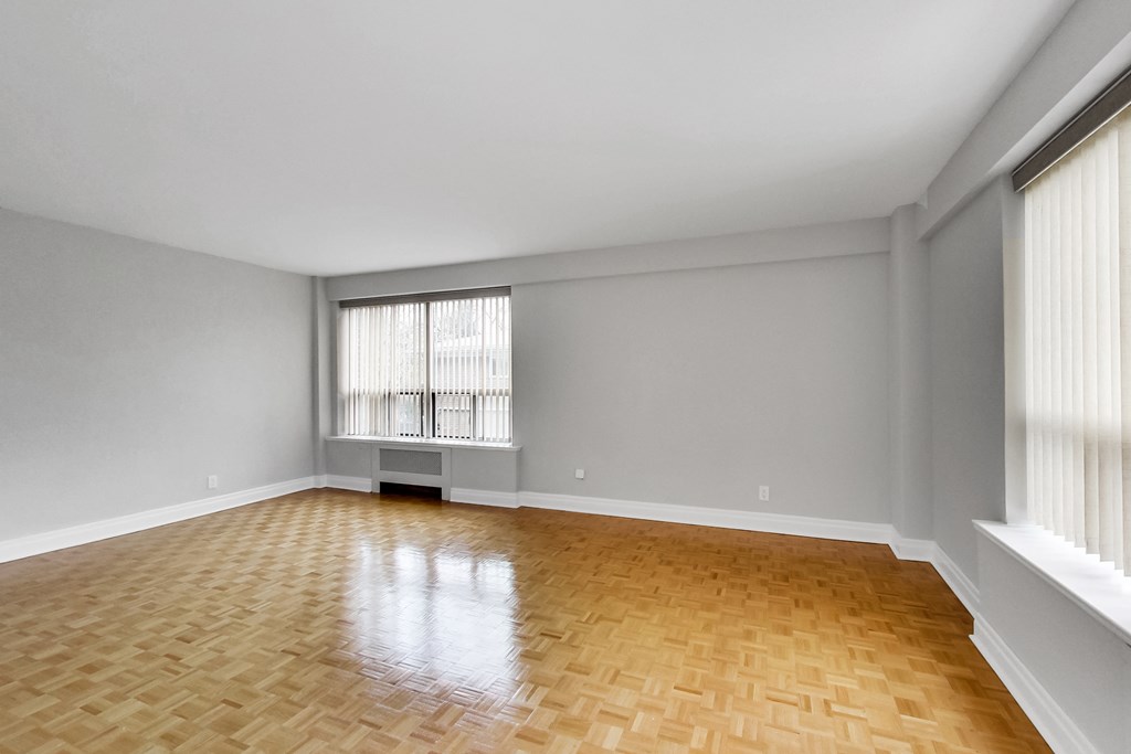 an empty living room with wood flooring and a window