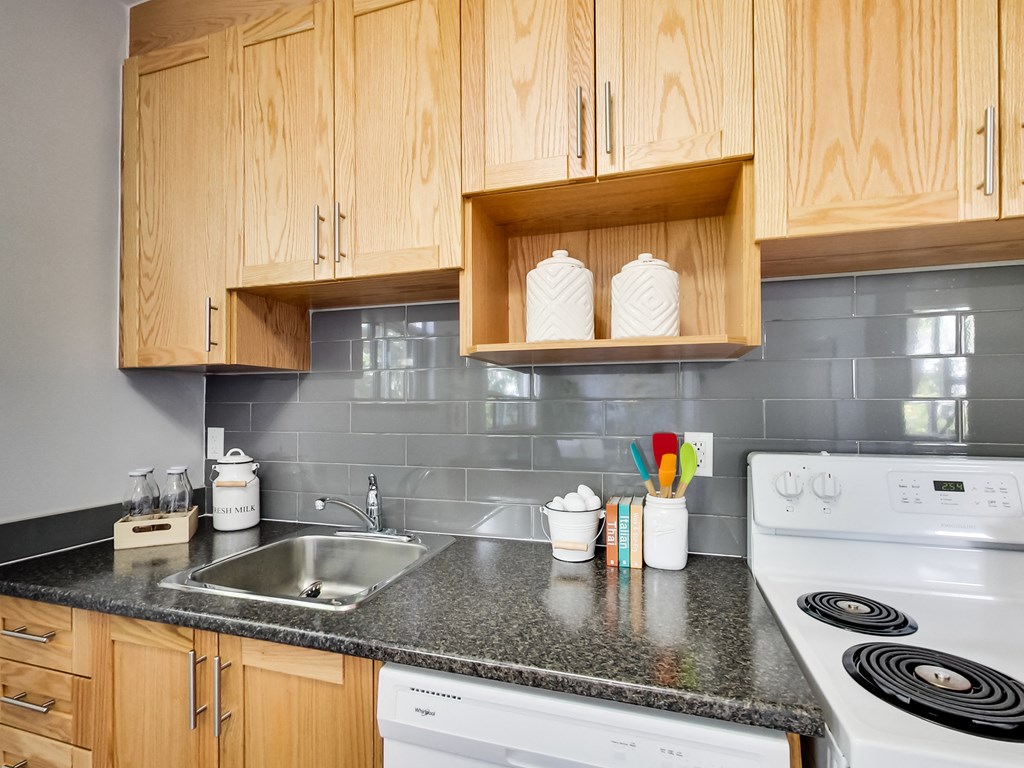 A kitchen with wooden cabinets and a white stove top oven.
