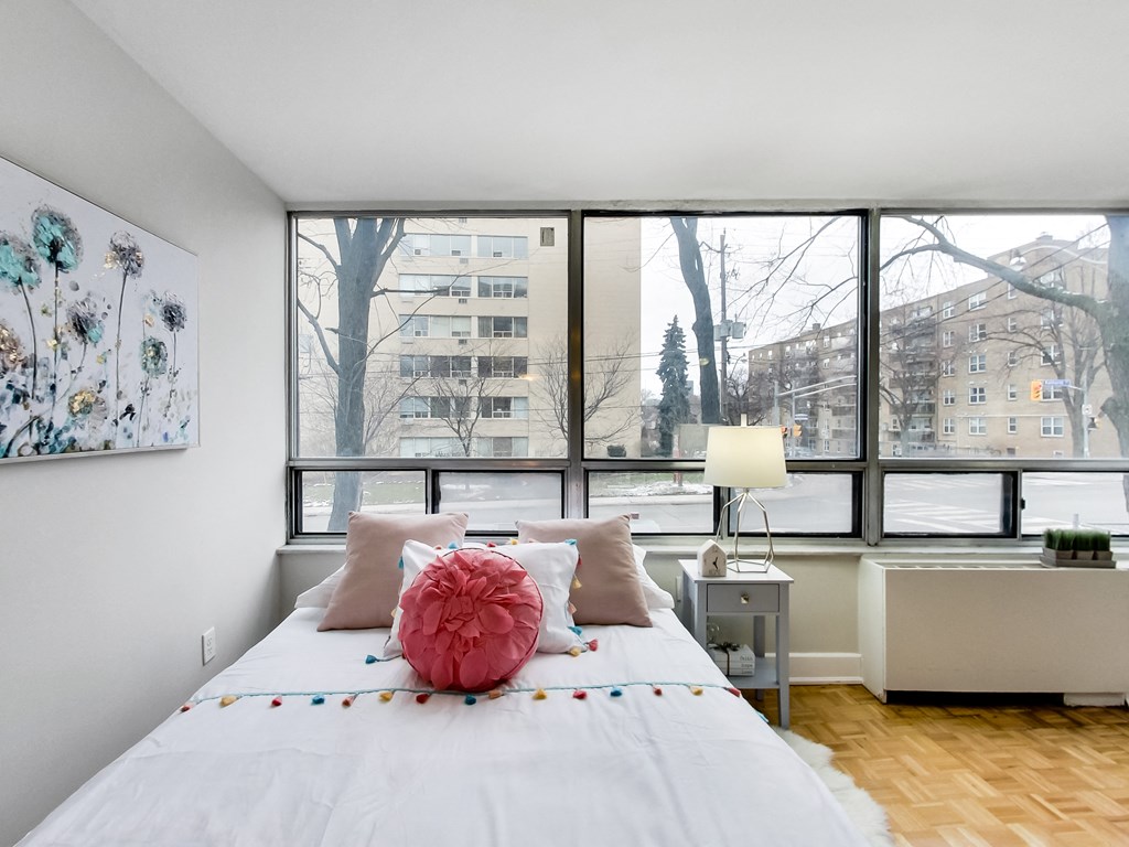 A bedroom with a large bed and a large window overlooking a snowy landscape.