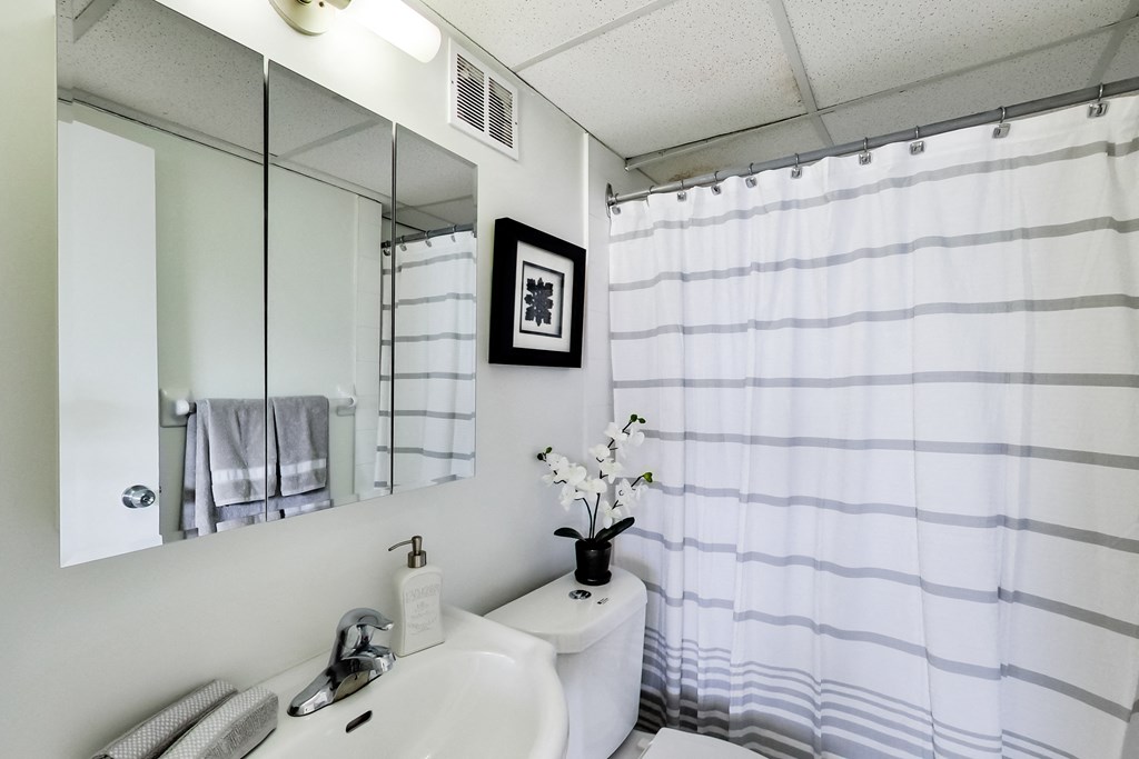 A white sink with a mirror above it and a towel hanging on the wall.