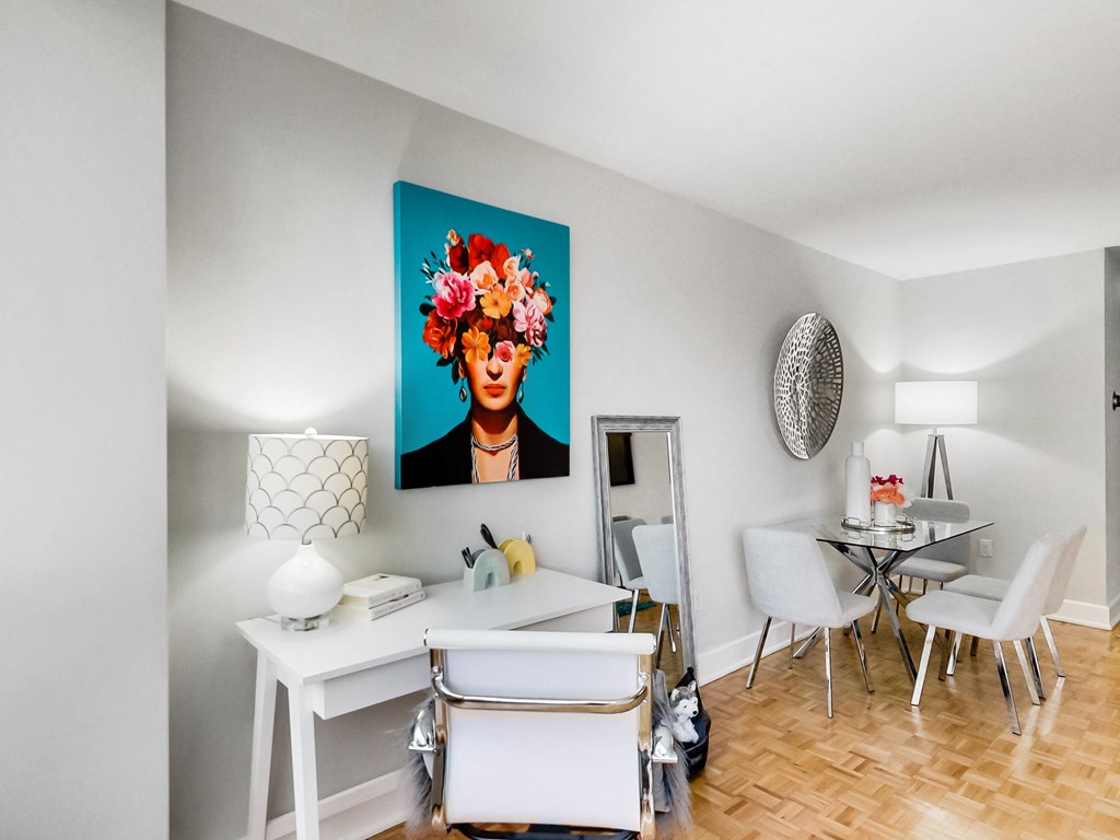 A dining room with a white table and chairs and a painting of a woman with flowers in her hair.