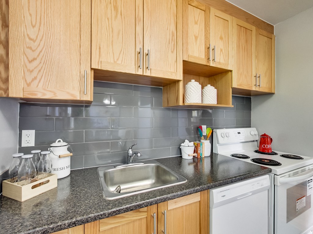 A kitchen with wooden cabinets and a white stove top oven.