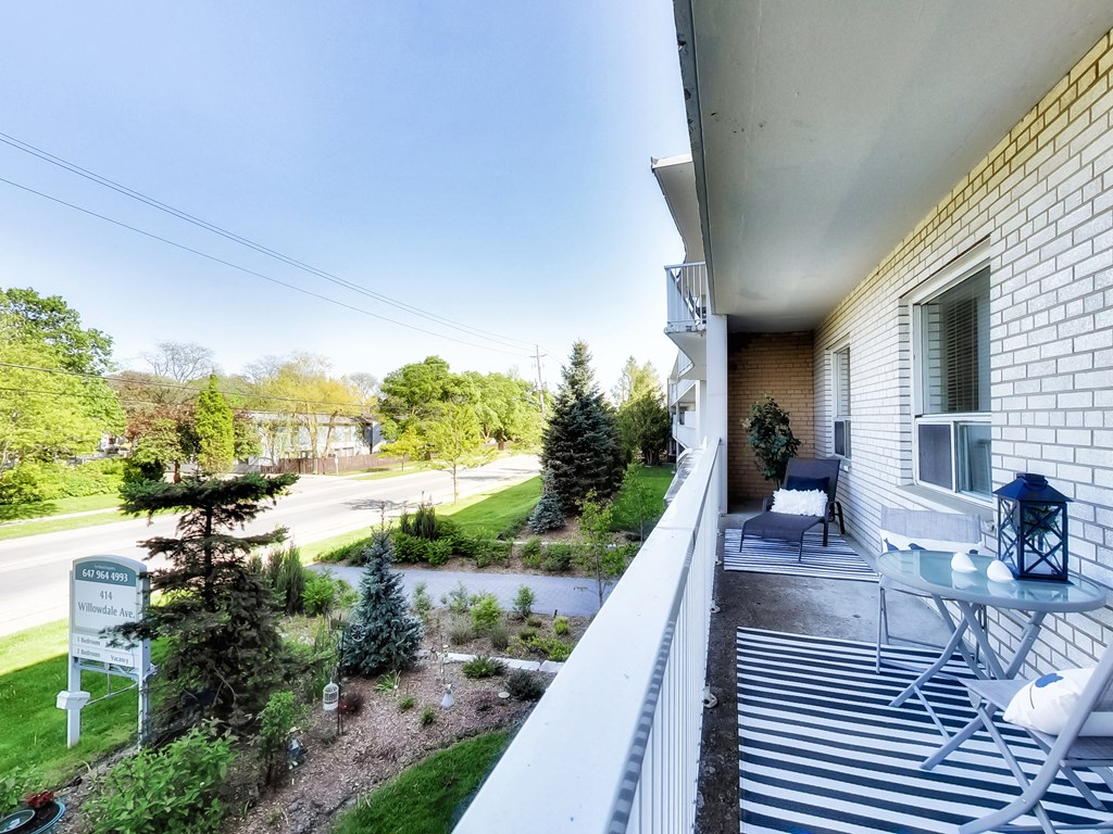 the view from the balcony of a white house with a patio and a garden