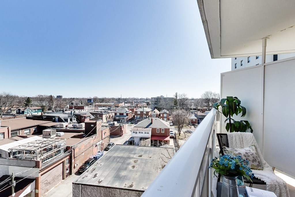 A balcony with a potted plant overlooks a cityscape.