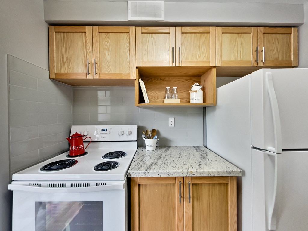 A kitchen with a white stove, wooden cabinets, and a marble countertop.