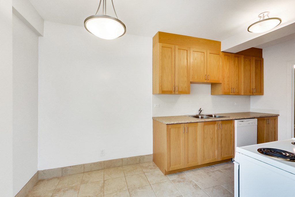 an empty kitchen with white appliances and wooden cabinets