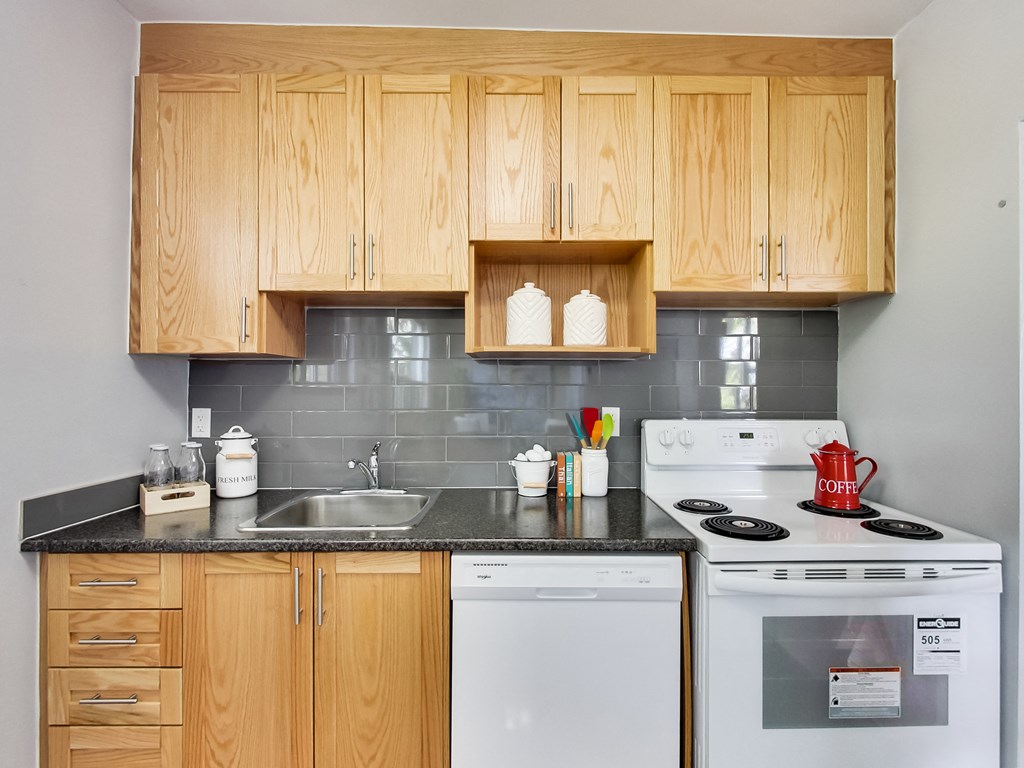 A kitchen with wooden cabinets and a white stove top oven.