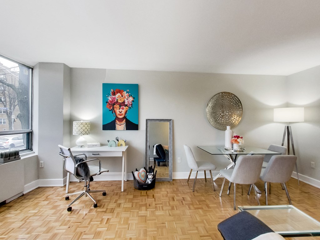 A room with a desk, chairs, and a painting on the wall.