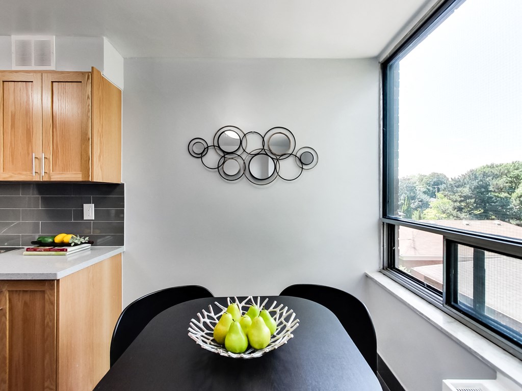 A bowl of fruit sits on a table in a kitchen.