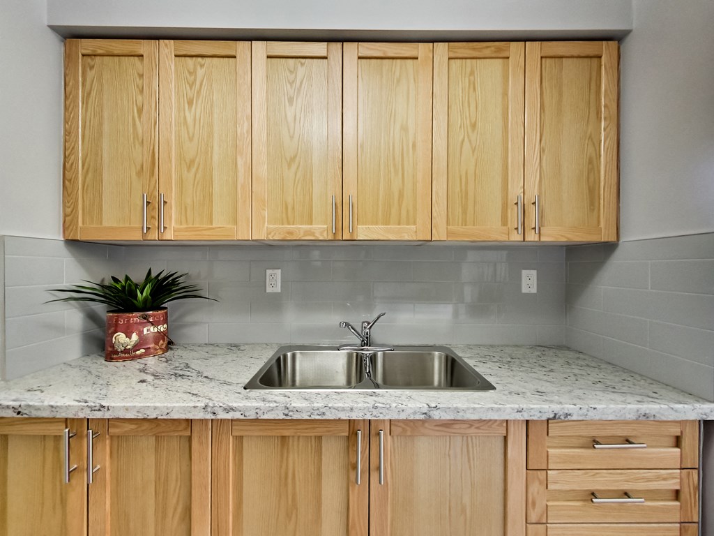 A kitchen with wooden cabinets and a marble countertop.