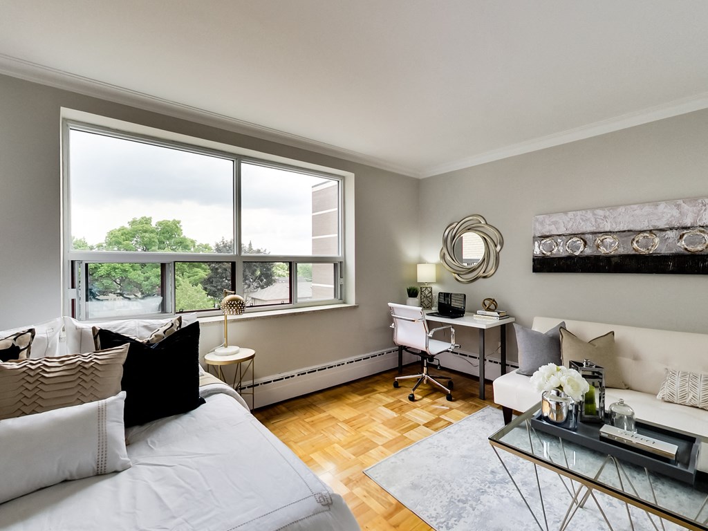 a living room with a couch and a desk and a window