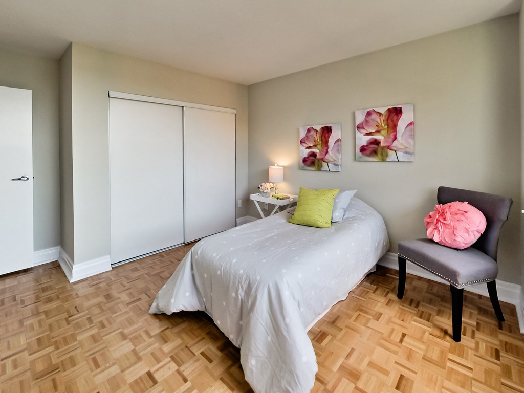 a bedroom with a bed and a chair and a wood floor