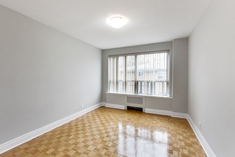 an empty living room with a large window and wooden floors
