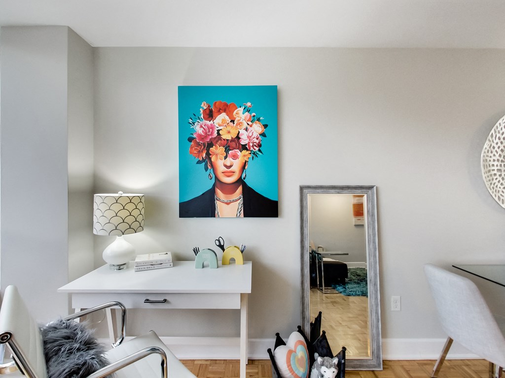 A room with a white desk and a painting of a woman with flowers in her hair.