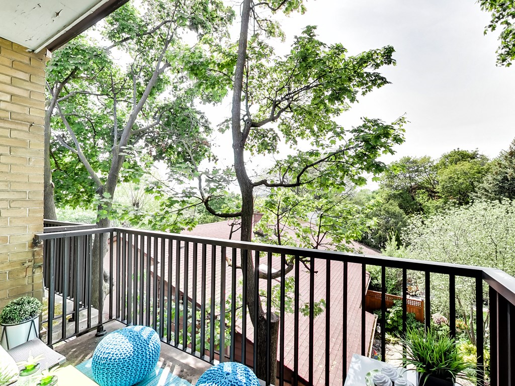 A balcony with a black railing and a blue chair.