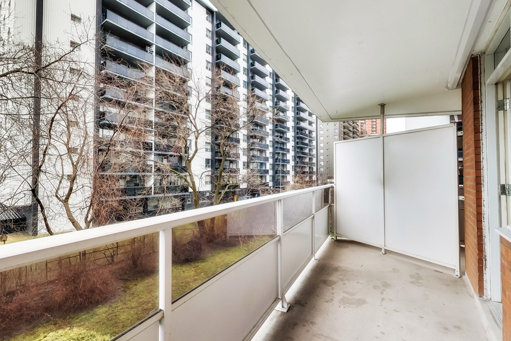 A balcony with a white railing and a view of a building with windows.