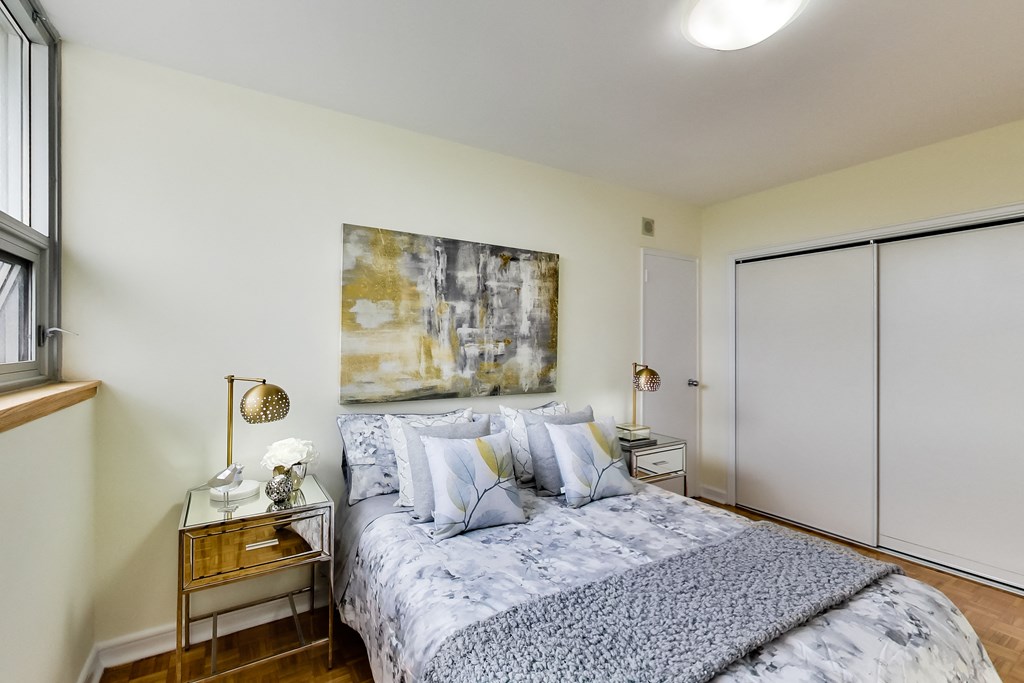 A bedroom with a bed, nightstand, and a painting on the wall.