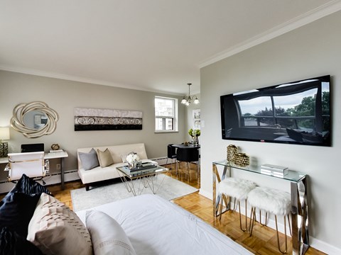 A living room with a white couch and a television on the wall.