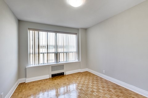 an empty living room with a large window and wood flooring
