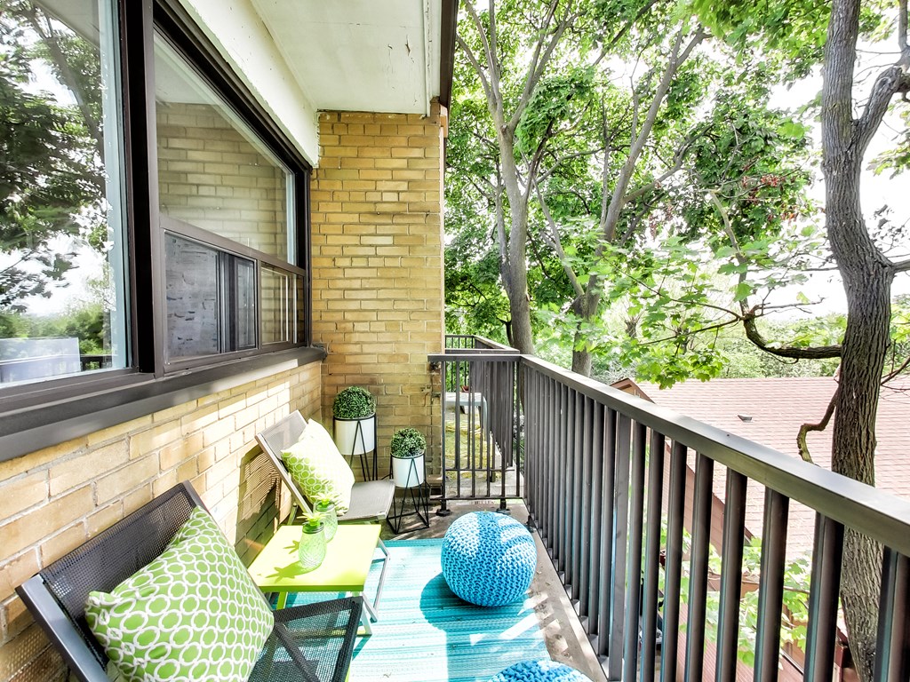 A balcony with a table and chairs and a view of a tree.