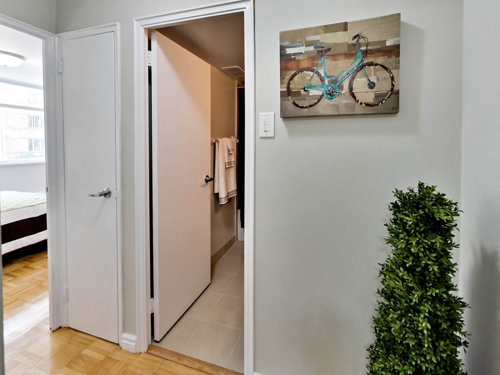 A white door is open to a hallway with a painting of a bike on the wall.
