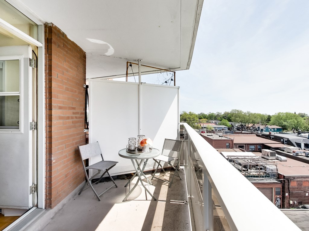A balcony with a table and chairs overlooking a cityscape.