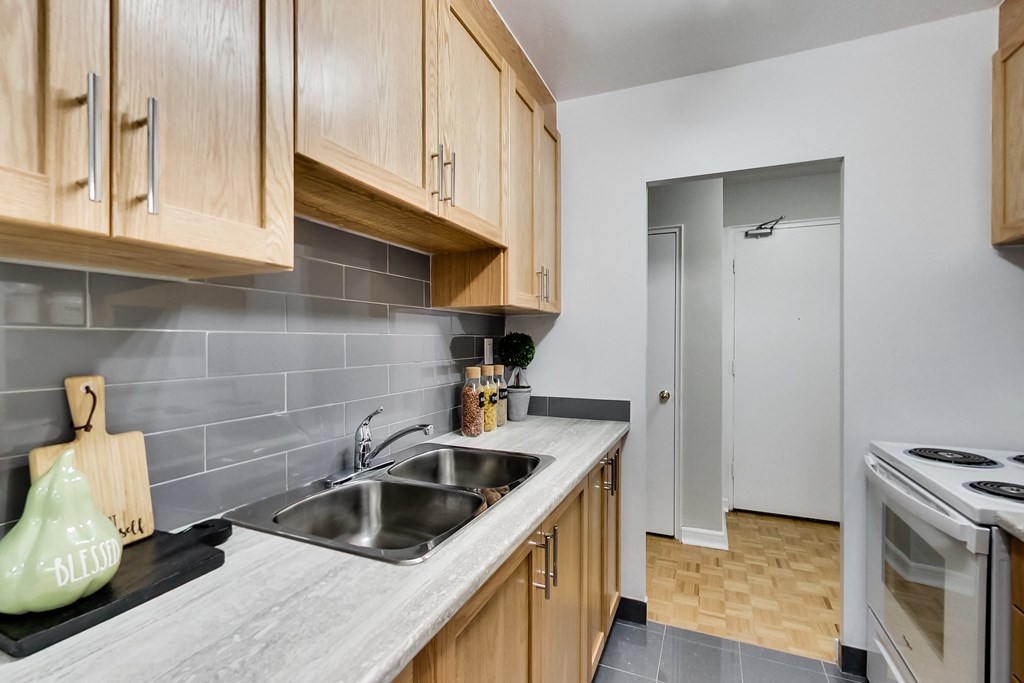 a kitchen with a sink and a stove and a door to a hallway