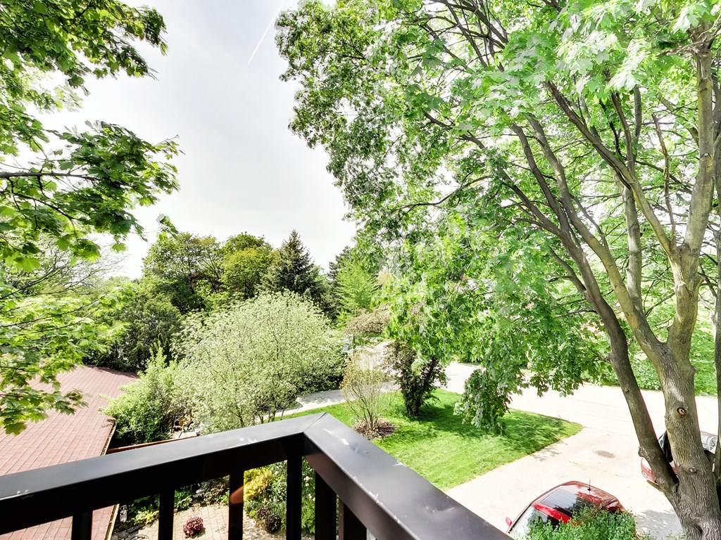 A balcony overlooks a lush green yard.