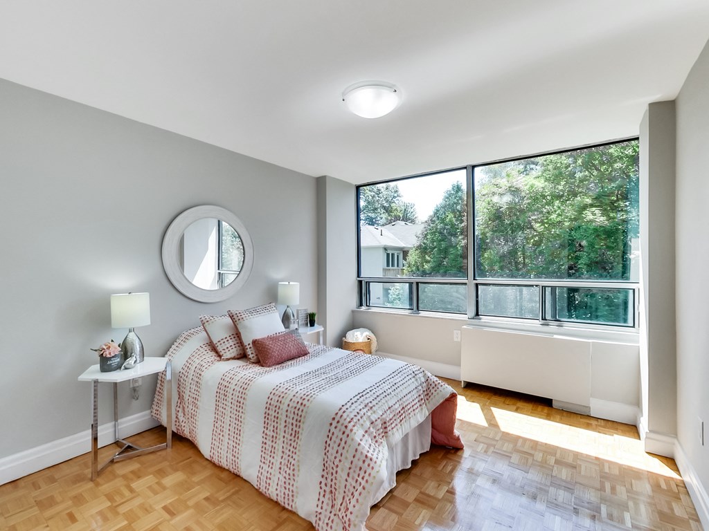A bedroom with a bed, nightstand, and a round mirror on the wall.