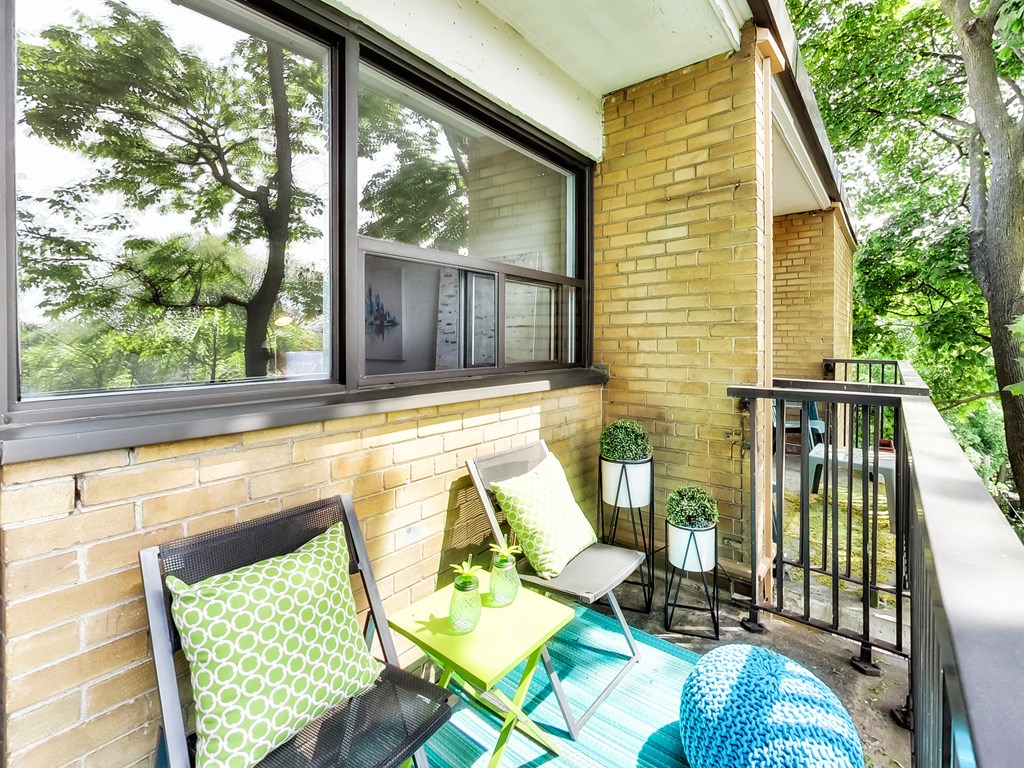 A balcony with a chair, table, and potted plant.
